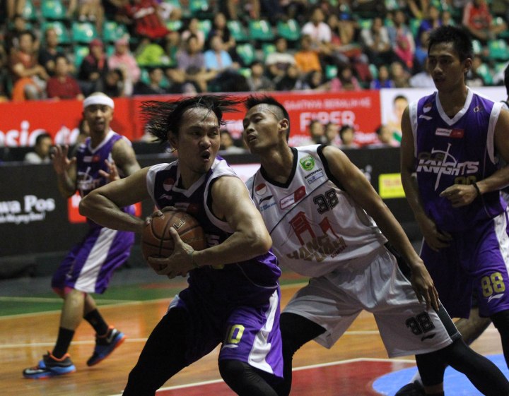 Small forward CLS Knights Surabaya Rachmad Febri Utomo (kiri) berusaha mempertahankan bola rebound dalam laga melawan Hangtuah Sumsel IM, Kamis (26/2).