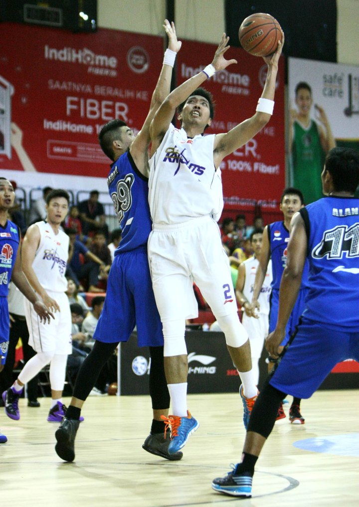 Power forward CLS Knights Surabaya Dwi Haryoko (tengah) berusaha melepaskan tembakan dalam hadangan Freddy (Bimasakti Nikko Steel Malang) dalam laga di Hi-Test Arena, Batam, Jumat (6/2).