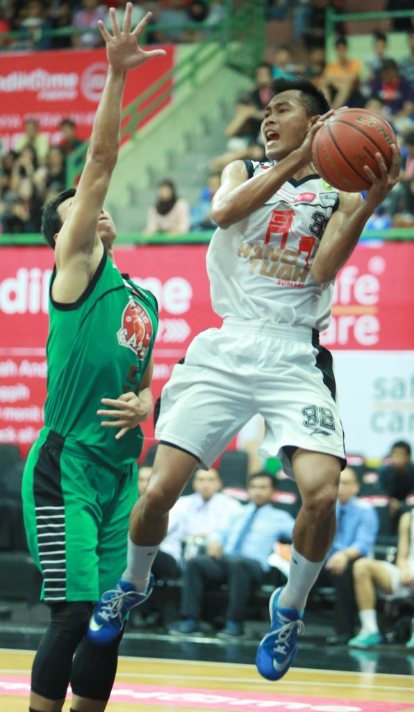 Small forward Hangtuah Sumsel IM Achmad Junaedi (kanan) melepaskan passing melewati penjagaan Dian Heryadi (Pacific Caesar Surabaya) dalam laga di GOR UNY, Jogjakarta, Minggu (15/3).