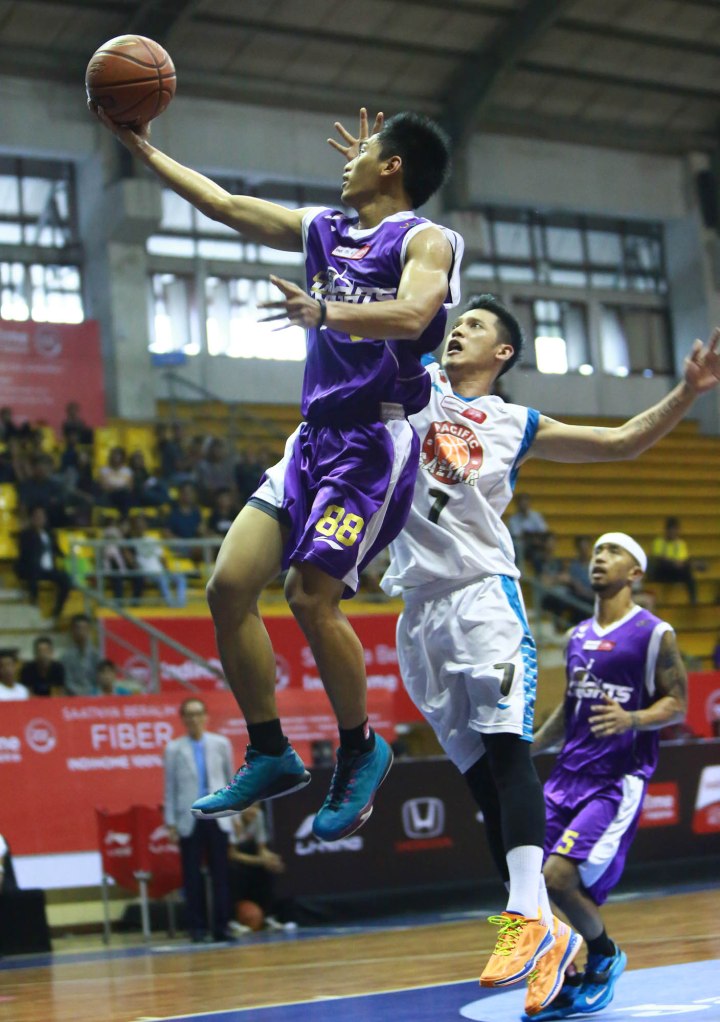 Shooting guard CLS Knights A.A. Ngurah Wisnu Budidharma S. (kiri) melakukan lay up melewati penjagaan Handoyo Cahyo Saputro (Pacific Caesar Surabaya) dalam laga di C-Tra Arena, Bandung, Minggu (29/3).