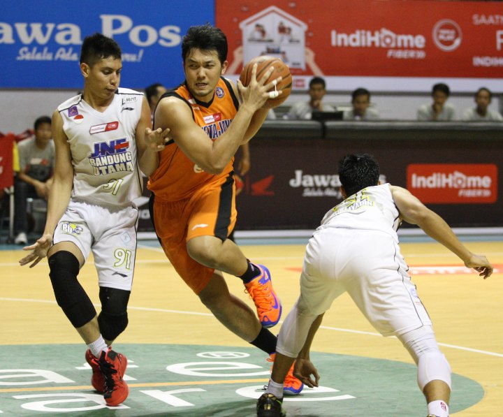 Power forward Pelita Jaya Energi Mega Persada Ponsianus Nyoman Indrawan (tengah) berusaha melewati penjagaan Azhari Rahmat (kiri) dan Surliyadin dari JNE BSC Bandung Utama dalam laga di DBL Arena, Surabaya, Kamis (9/4).