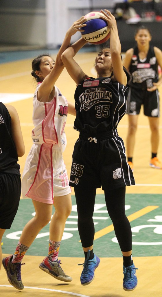 Small forward Merah Putih Predators Jakarta Yuningsih (kanan) berusaha melepaskan tembakan dihadang Jesslyn Tedja dari Rajawali Bandung dalam laga di DBL Arena, Surabaya, Jumat (10/4).